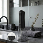 Black dental water flosser on a bathroom counter with a sink and mirror in the background.