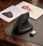 A black wireless ergonomic mouse with a small USB receiver, shown on a dark desk mat with a product manual and branded card on a wooden table. The brand name Radex is visible on the card.