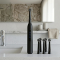 Black electric toothbrush with multiple heads on a bathroom counter