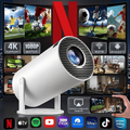 A white cylindrical smart projector shown on a dark promotional background with many app and scene thumbnails, including Netflix, 4K support, WiFi, Android 11, Airplay, Miracast, Apple TV, Spotify, YouTube, HBO Max, Disney+, and Prime Video.